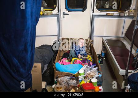 KIEV, UCRAINA - 13 marzo 2022: Guerra in Ucraina. Vita in un rifugio bomba stazione metropolitana Palace Ucraina. Bambino in una scatola di cartone in una macchina della metropolitana Foto Stock