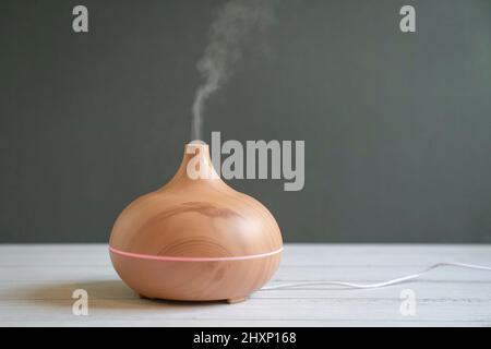 Diffusore di olio essenziale aromatizzato sul tavolo. Sfondo grigio, spazio di copia. Foto Stock