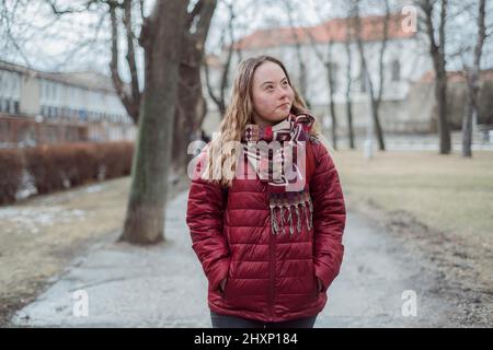 Giovane studentessa con sindrome di Down che cammina per strada in inverno Foto Stock