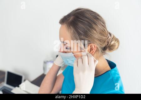 Bella donna medico o infermiere indossare maschera protettiva e guanti in lattice o gomma in interni. Foto di alta qualità Foto Stock