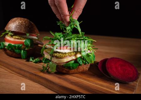 Buon Vegan Burger. Hamburger su un tavolo di legno. Chef che cucinano gustosi sandwich. Foto Stock