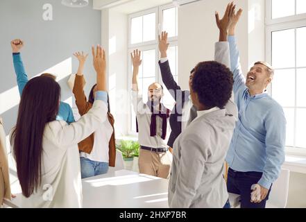 Un team diversificato di persone d'affari felici che si trovano in ufficio, celebrando il successo e divertendosi Foto Stock