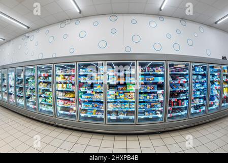 Fossano, Italia - 12 marzo 2022: Vetrine refrigerate con pacchetti di cibi surgelati al supermercato MERCATÒ italiano, fish eye vision Foto Stock