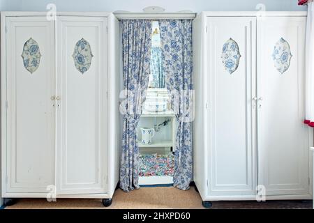 guardaroba in legno bianco con ingresso ricurlato a un piccolo bagno storico Foto Stock