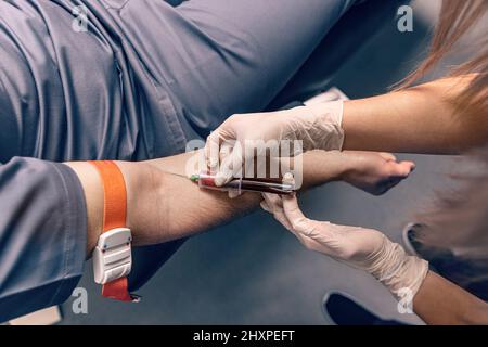 Nurse che prende un campione di sangue dalla vena del braccio con un vacutainer. Procedura di venipuntura o venopuntura Foto Stock