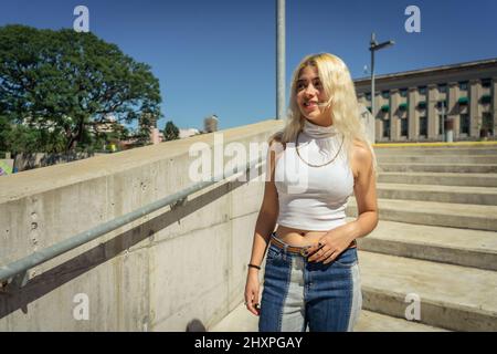 Giovane donna latina che cammina lungo una grande scala. Foto Stock