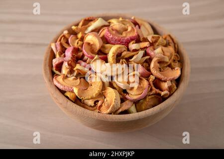 Ciotola piena di mele secche su sfondo di legno Foto Stock