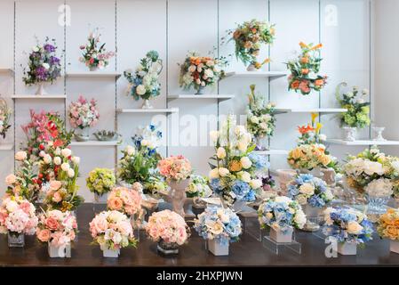 Bouquet decorativi di fiori colorati sulla vetrina del negozio. Foto Stock