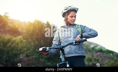 Controllare il suo tempo. Sparato di una mountain bike femminile fuori per un giro di prima mattina. Foto Stock