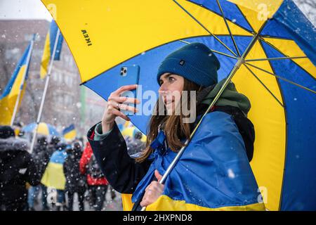 Toronto, Canada. 13th Mar 2022. Durante la dimostrazione, un manifestante scatta foto tenendo un ombrello a colori della bandiera Ucraina. Migliaia di marzo al Consolato degli Stati Uniti per un rally "No Fly zone" a Toronto, Canada. Le proteste globali sono state organizzate in tutto il mondo a seguito dell'invasione russa dell'Ucraina. (Foto di Katherine Cheng/SOPA Images/Sipa USA) Credit: Sipa USA/Alamy Live News Foto Stock