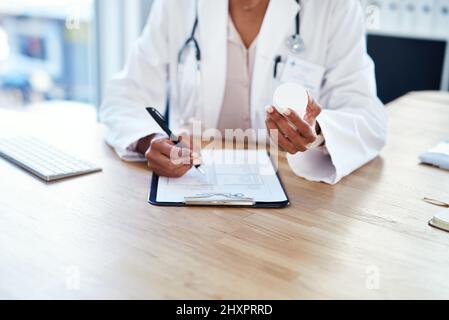 Invia i suoi pazienti a casa ben attrezzati per il recupero. Shot di un medico giovane che compila un modulo per una prescrizione nella sua stanza di consulenza. Foto Stock