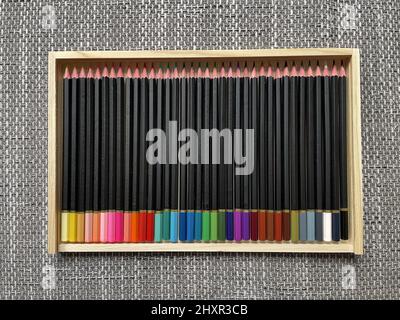 Diversi pastelli colorati disposti in una scatola di legno. Foto Stock