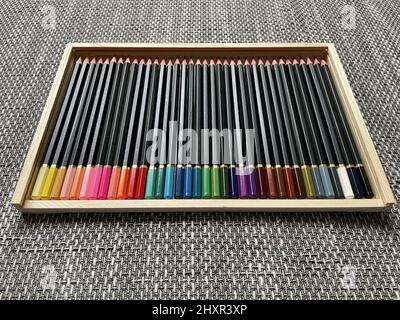 Diversi pastelli colorati disposti in una scatola di legno. Foto Stock
