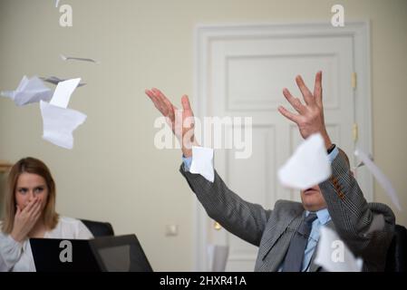 Senior businessman sitting at roundtable meeting and tear document Foto Stock