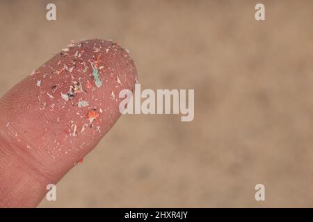 Pellet di plastica piccolo su dito. Micro plastica, problema. Foto Stock