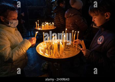 Lviv, Ucraina. 13th Mar 2022. I bambini hanno acceso le candele durante le preghiere all'interno della Chiesa. Nella chiesa dei Santi Pietro e Paolo, la chiesa storica di Lviv, si tenevano preghiere per lutto per gli ucraini che erano scomparsi e pregavano per la pace. Credit: SOPA Images Limited/Alamy Live News Foto Stock