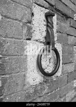 Antico cerchio di ferro appeso su un muro di pietra Foto Stock