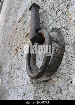 Antico cerchio di ferro appeso su un muro di pietra Foto Stock