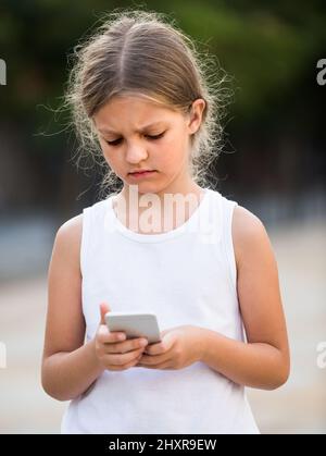ragazza preoccupata guardando il telefono Foto Stock