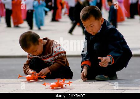 Bambini che giocano con aerei di plastica in una piazza di Pyongyang, Corea del Nord Foto Stock