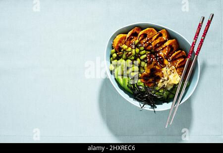 ciotola di sushi vegano con patate dolci al forno, fagioli di edamame, avocado e salsa al succo. alternativa sana Foto Stock