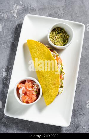 mais tacos con salmone, maionese e pistacchi su un tavolo di cemento Foto Stock