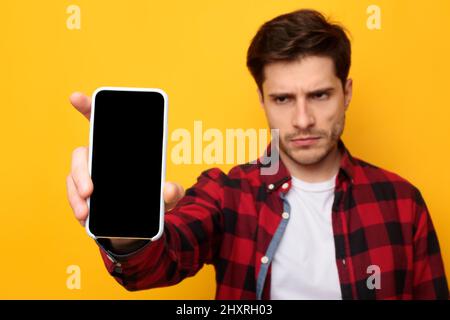 Un ragazzo triste che tiene in mano lo schermo dello smartphone vuoto Foto Stock