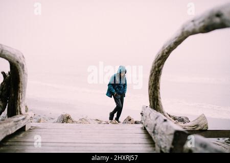 Ragazzo teen in Hooded Raincoat cammina con le mani in tasca Foto Stock