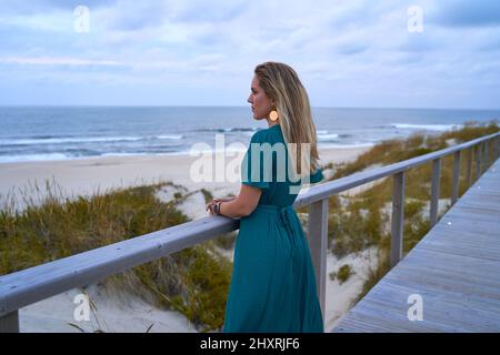 bella ed elegante ragazza che guarda penosamente al mare Foto Stock