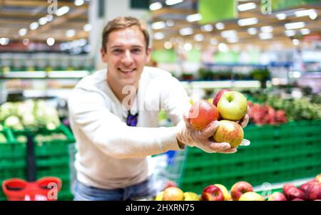 Giovane uomo singolo che mostra frutta e verdura allo shopping nel supermercato negozio di alimentari - moderno concetto di stile di vita sano con ragazzo sul bio-cibo Foto Stock