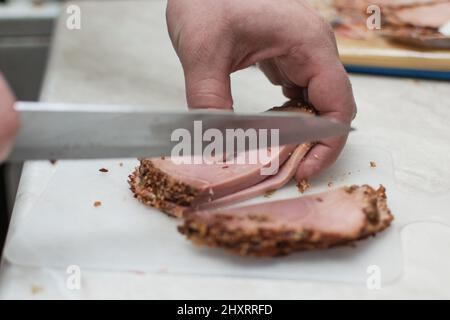 Maschio mani taglio prosciutto, carne preparata su un tagliere. Foto Stock