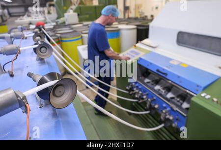 14 marzo 2022, Sassonia, Oederan: Un dipendente controlla la cardatura del cotone in tamponi di cotone per la produzione di tamponi di cotone presso il leader di mercato Lemoine. L'azienda, che conta 100 dipendenti, si affida maggiormente alla carta anziché alla plastica per l'imballaggio. A tal fine, nello stesso giorno è stata messa in funzione una nuova linea di confezionamento. I tamponi di cotone sono ora imballati in sacchetti di carta invece di sacchetti di plastica prima che siano venduti in drogherie e supermercati. Il nuovo imballaggio è realizzato con carta riciclata al 100% ed è prodotto interamente in Sassonia. Secondo la società, più di due milioni di euro Foto Stock