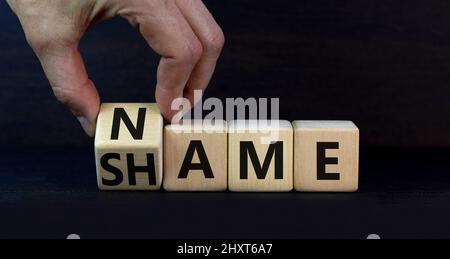 Nome o simbolo di vergogna. Businessman trasforma il cubo di legno e cambia la parola concetto vergogna in Nome. Bella tabella grigia sfondo grigio, spazio di copia. Foto Stock