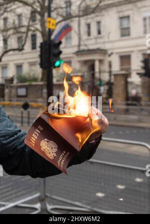 Un cittadino russo brucia il suo passaporto russo tra i manifestanti fuori dall'ambasciata russa a Londra per protestare contro la guerra Ucraina. Foto Stock