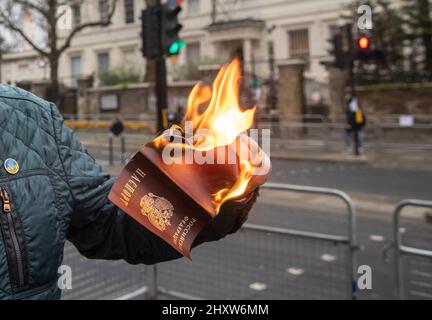 Un cittadino russo brucia il suo passaporto russo tra i manifestanti fuori dall'ambasciata russa a Londra per protestare contro la guerra Ucraina. Foto Stock