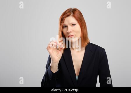 La donna di mezza età mostra il gesto ok sullo sfondo grigio dello studio, foto con posto per il testo Foto Stock