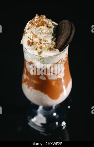 Colpo verticale di un milkshake al caramello su sfondo nero. Foto Stock