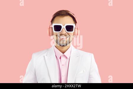 Ritratto di giovane sorridente in moderne cuffie stereo isolate su sfondo rosa. Foto Stock