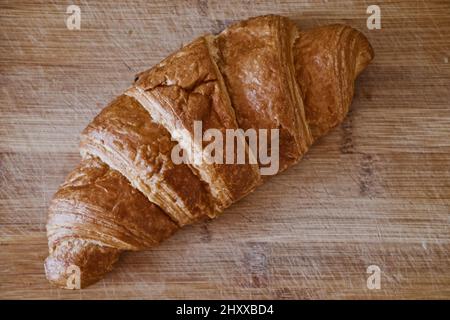 Primo piano di croissant appena sfornato su un tavolo di legno. Vista dall'alto, disposizione piatta. Foto Stock