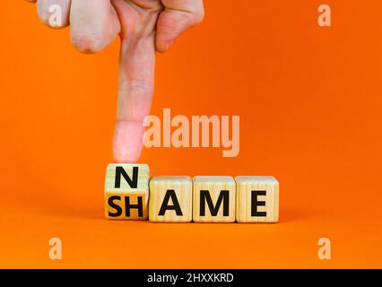 Nome o simbolo di vergogna. Businessman trasforma il cubo di legno e cambia la parola concetto vergogna in Nome. Bella tavola arancione sfondo arancione, copia spa Foto Stock