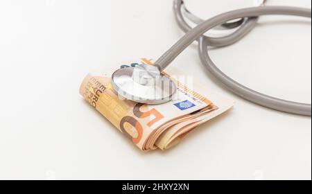 Salute e costo della medicina. Stetoscopio medico su denaro, pila di banconote in euro isolato su bianco, primo piano. Prezzo sanitario in Europa Foto Stock