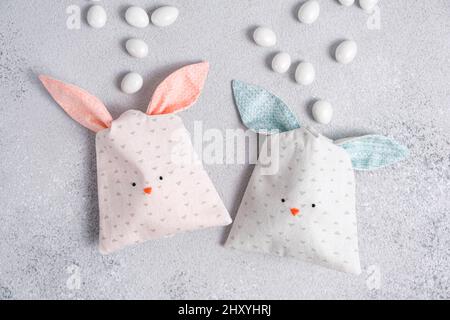 Due bustine di dolci a forma di coniglietto pasquale con orecchie blu e rosa su sfondo grigio chiaro. Imballaggio di tessuto di cotone in forma di bunnys carino o. Foto Stock