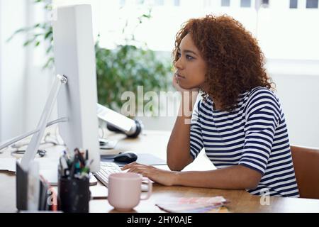 Questo progetto sta prendendo molto tempo. Scatto di una giovane donna al lavoro su un computer in un ufficio. Foto Stock