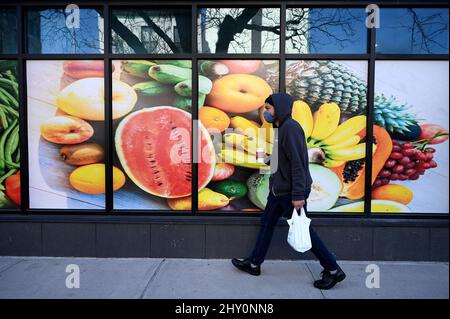 New York, Stati Uniti. 14th Mar 2022. Un uomo cammina davanti a una grande immagine stampata di frutta sul lato di un negozio di alimentari nel quartiere di New York City di Queens, NY, 14 marzo 2022. L’inflazione ha fissato un nuovo record di 40 anni al 7,9%, dal momento che l’impennata dei prezzi del petrolio segnala avvertimenti di recessione e le Nazioni Unite hanno avvertito che i prezzi dei prodotti alimentari globali potrebbero aumentare del 20% a causa del conflitto in Ucraina. (Foto di Anthony Behar/Sipa USA) Credit: Sipa USA/Alamy Live News Foto Stock