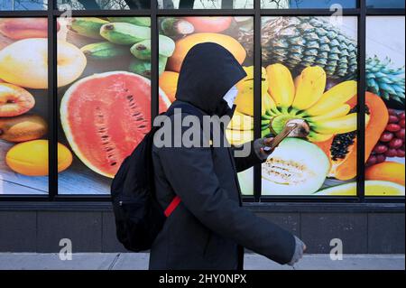 New York, Stati Uniti. 14th Mar 2022. Un uomo cammina davanti a una grande immagine stampata di frutta sul lato di un negozio di alimentari nel quartiere di New York City di Queens, NY, 14 marzo 2022. L’inflazione ha fissato un nuovo record di 40 anni al 7,9%, dal momento che l’impennata dei prezzi del petrolio segnala avvertimenti di recessione e le Nazioni Unite hanno avvertito che i prezzi dei prodotti alimentari globali potrebbero aumentare del 20% a causa del conflitto in Ucraina. (Foto di Anthony Behar/Sipa USA) Credit: Sipa USA/Alamy Live News Foto Stock