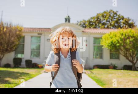 Divertente viso ragazzo scuola. Bambino pupul con zaini nel parco vicino a scuola. Scolaro con zaini all'aperto. Foto Stock