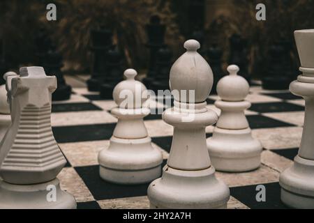 Primo piano di scacchi giganti pezzi su una scacchiera all'aperto - ottimo per sfondi Foto Stock
