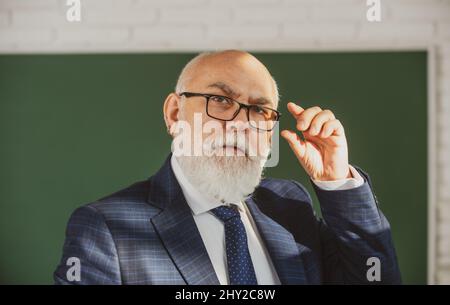 Insegnante di uomo anziano su una lavagna vuota durante la lezione, lezione di insegnamento all'università. Pensi il senior. Giornata degli insegnanti. Foto Stock