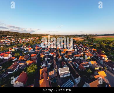 Veduta aerea di una città con case rosse sul tetto circondate da verdi valli e foreste Foto Stock
