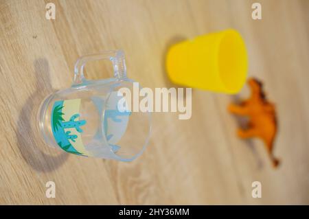 Vetro vuoto su un tavolo di legno con tazza e dinosauro giocattolo. Foto Stock